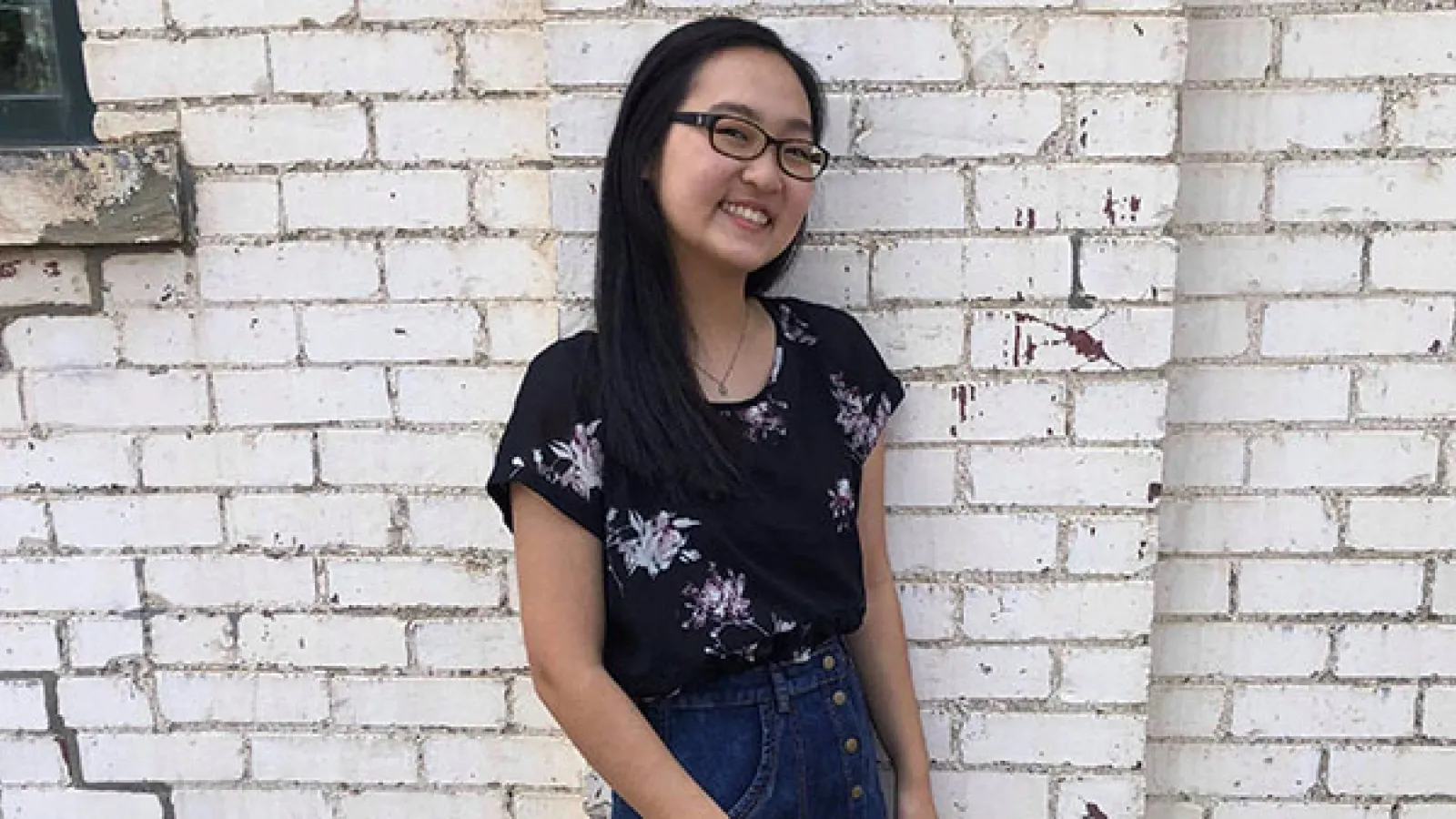 Photograph of Deborah next to a brick wall